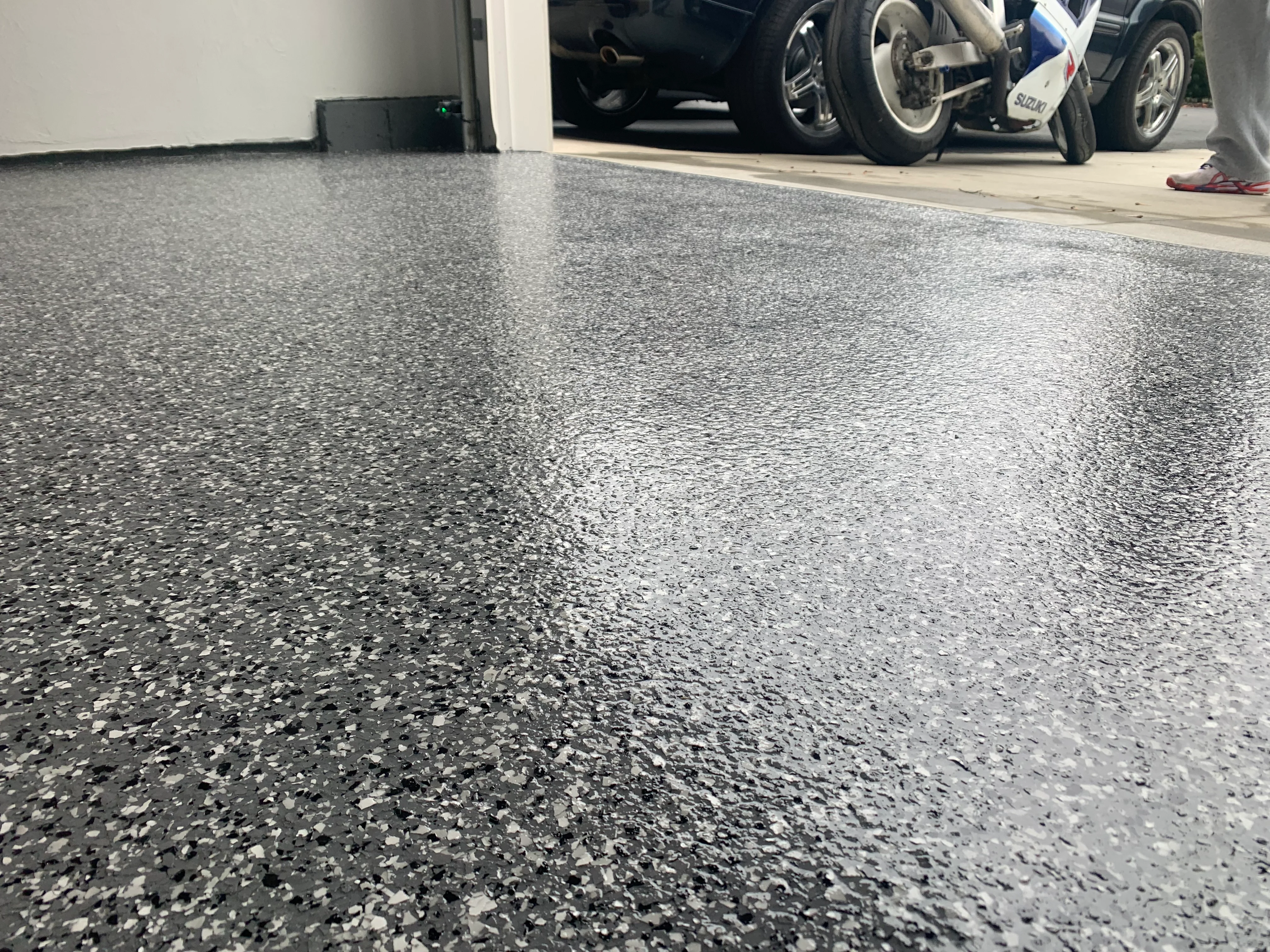 Speckled gray and white epoxy garage floor with vehicles in background
