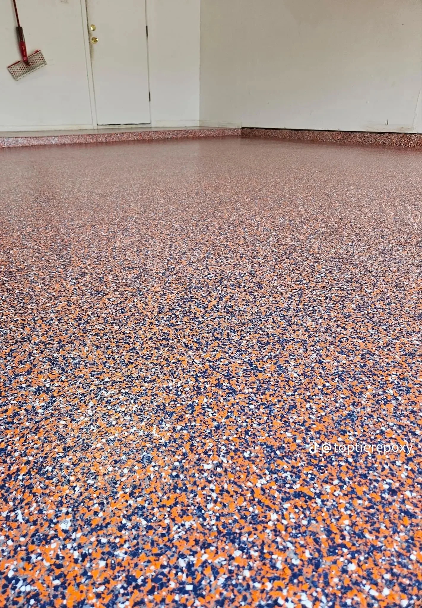 Orange, navy, and white epoxy flake flooring with seamless finish and colored chip aggregate