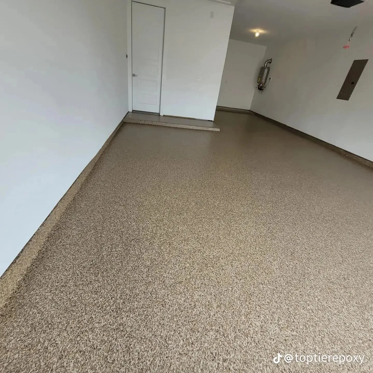 Newly installed gray epoxy floor coating in commercial space with white walls and metal door frame