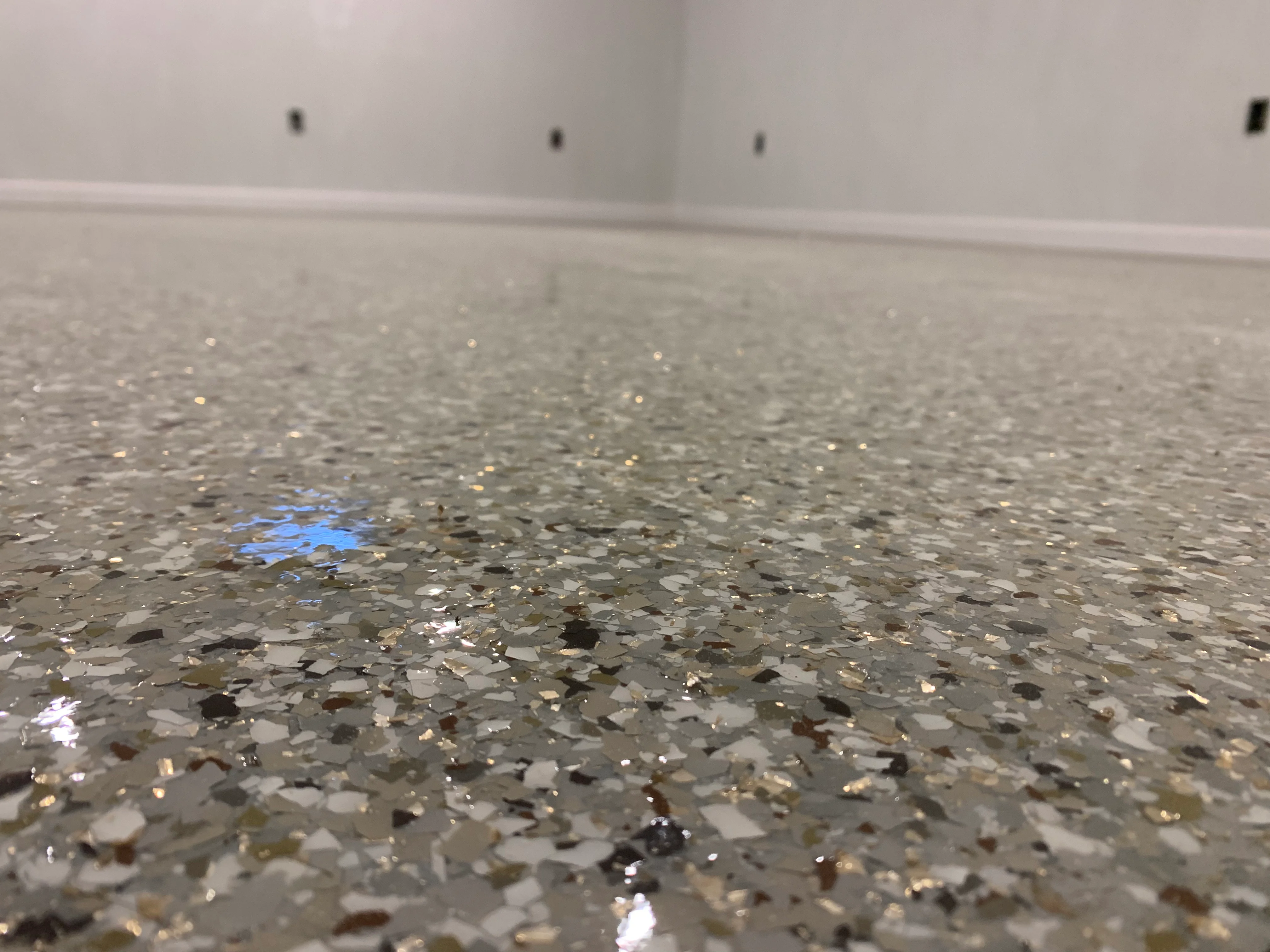 Creekbed-style epoxy floor with aggregate, metallic flakes, and blue accent details