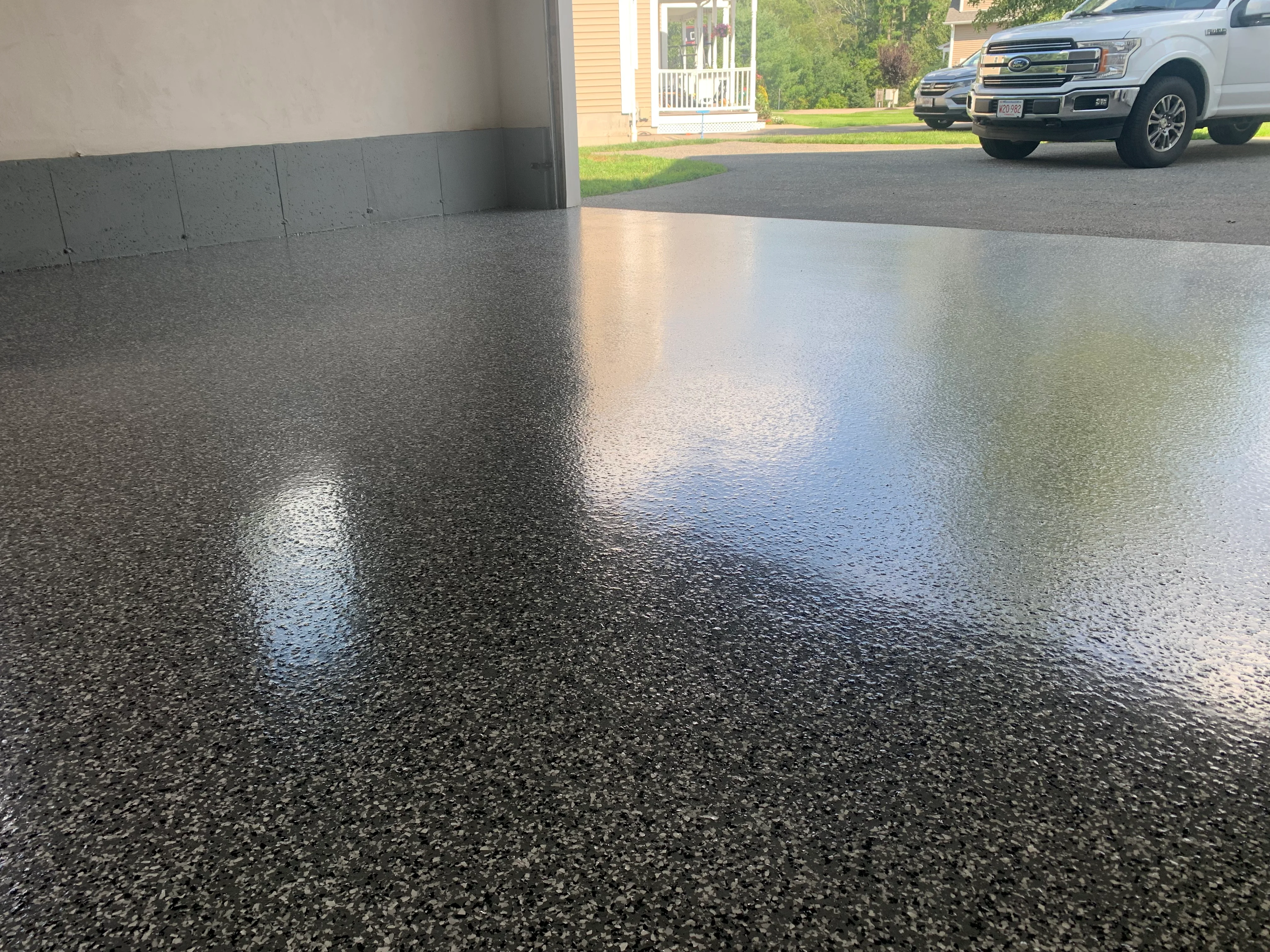 Polished epoxy garage floor with dark aggregate, high-gloss finish reflecting light
