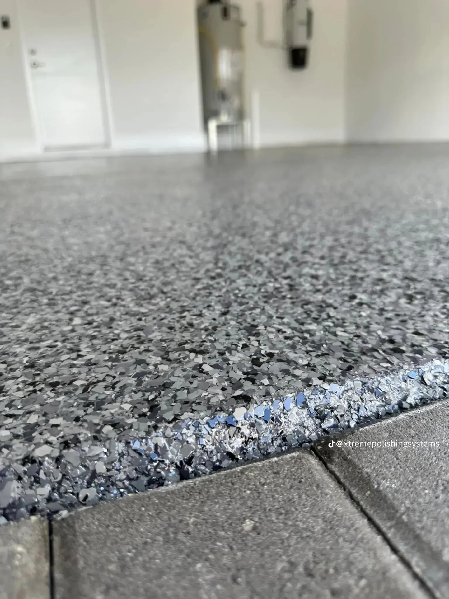 Gray epoxy floor with blue and white decorative flakes and metal trim edge
