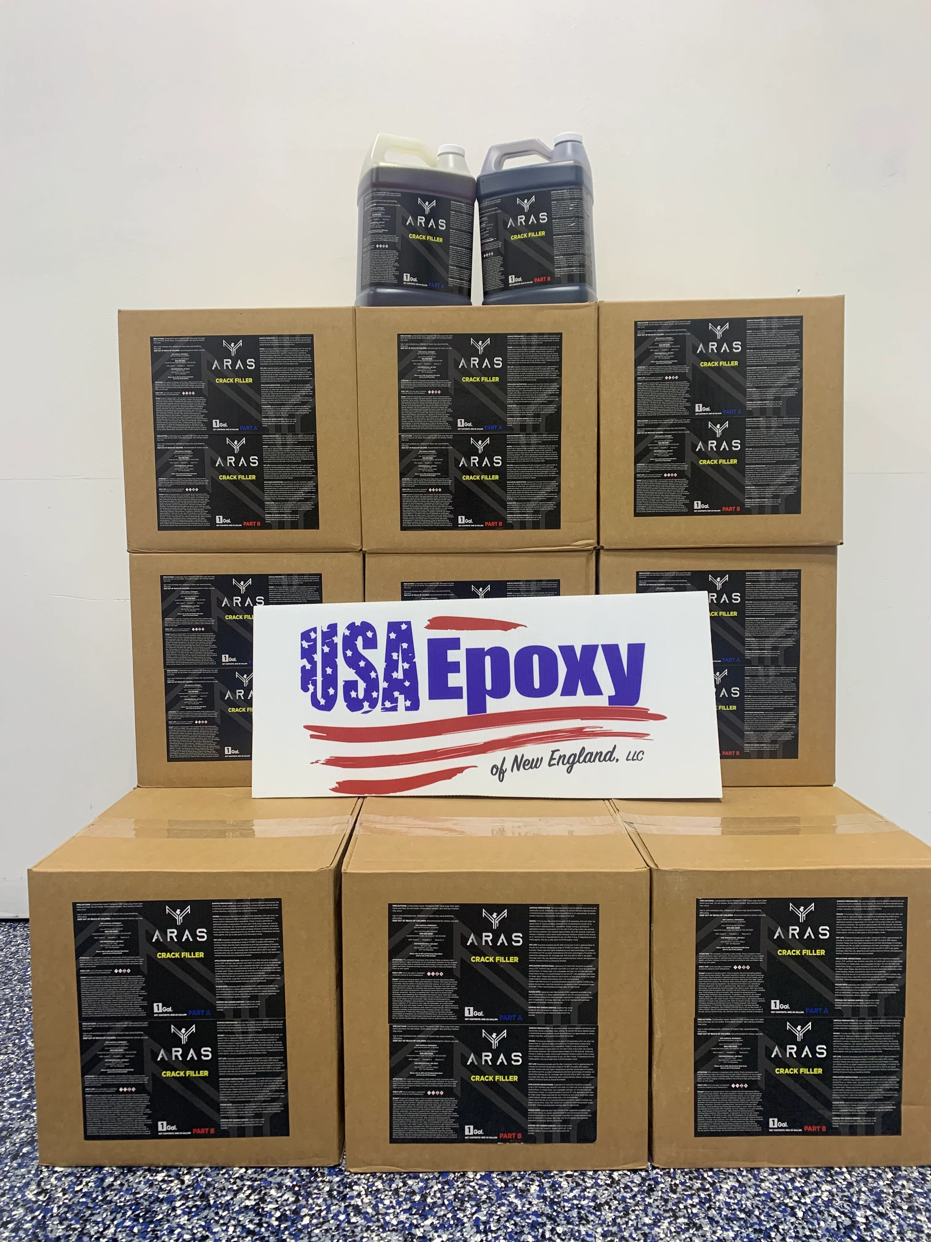 Stacked cardboard boxes of Aras Crack Filler epoxy product with liquid containers and USA Epoxy branding