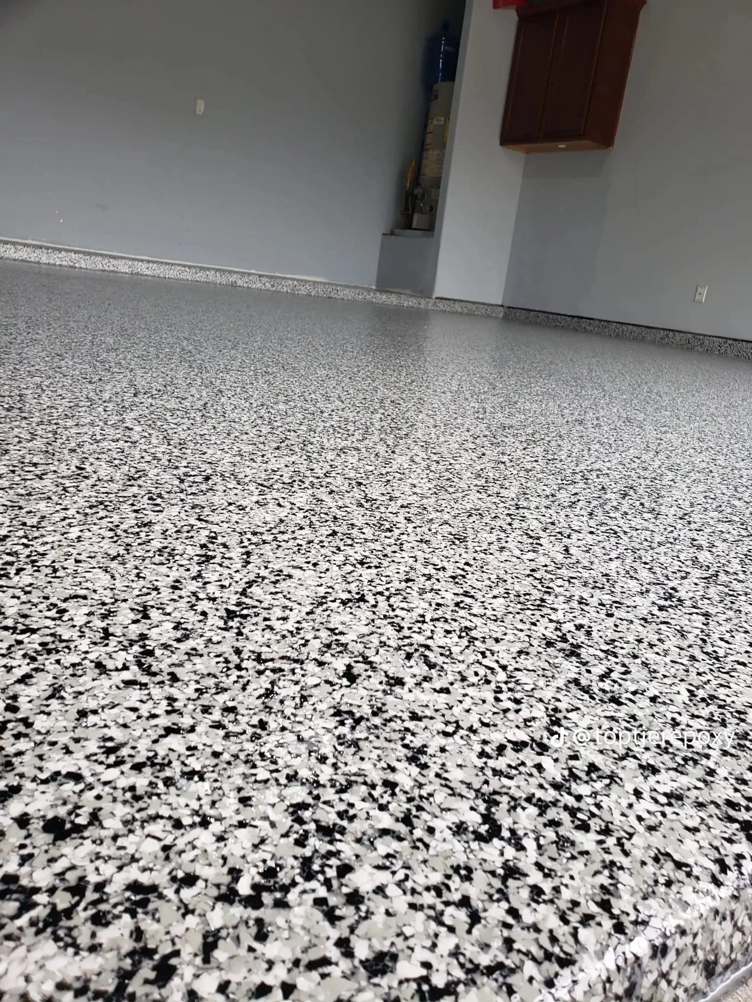White and black speckled epoxy garage floor with metallic trim and finished walls
