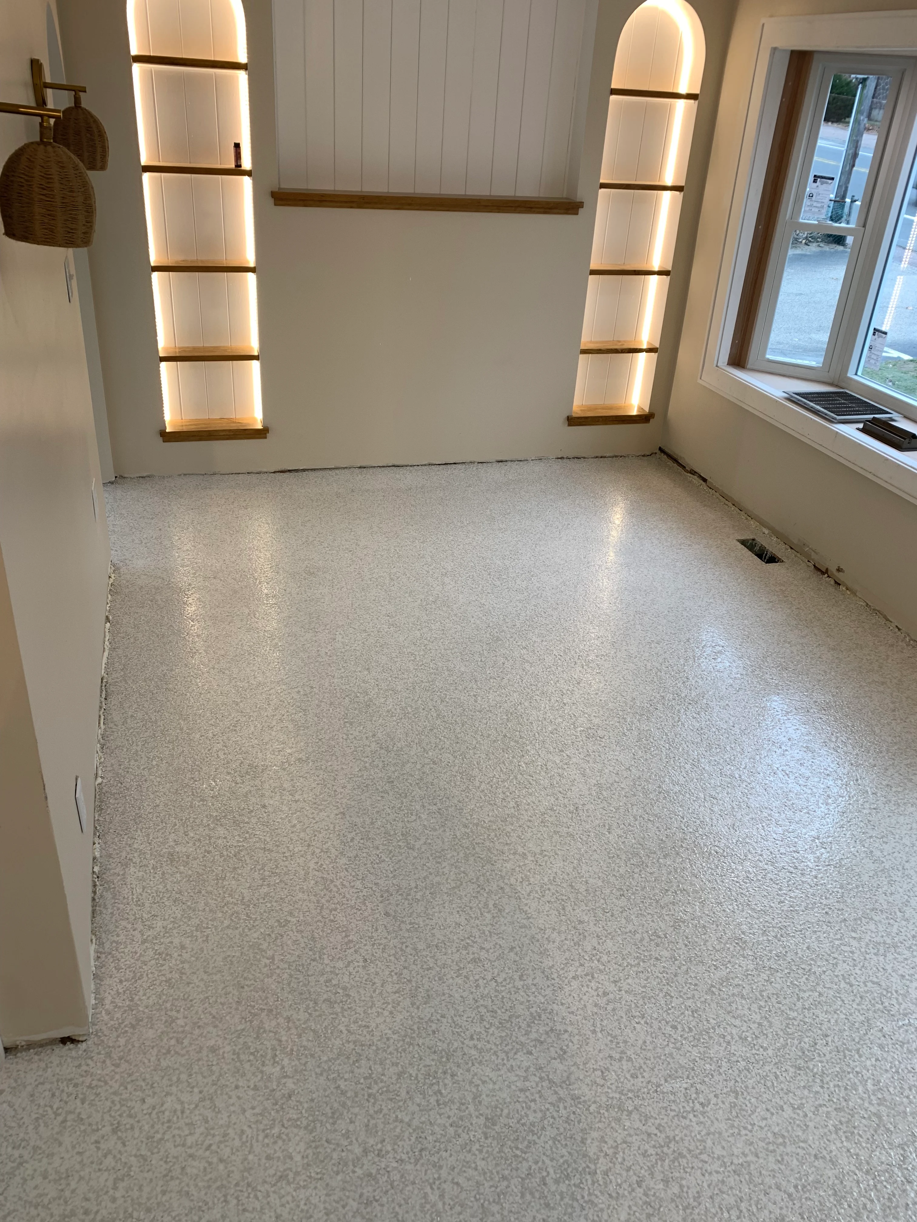 Light gray epoxy floor with LED-lit wooden shelving and white shiplap walls
