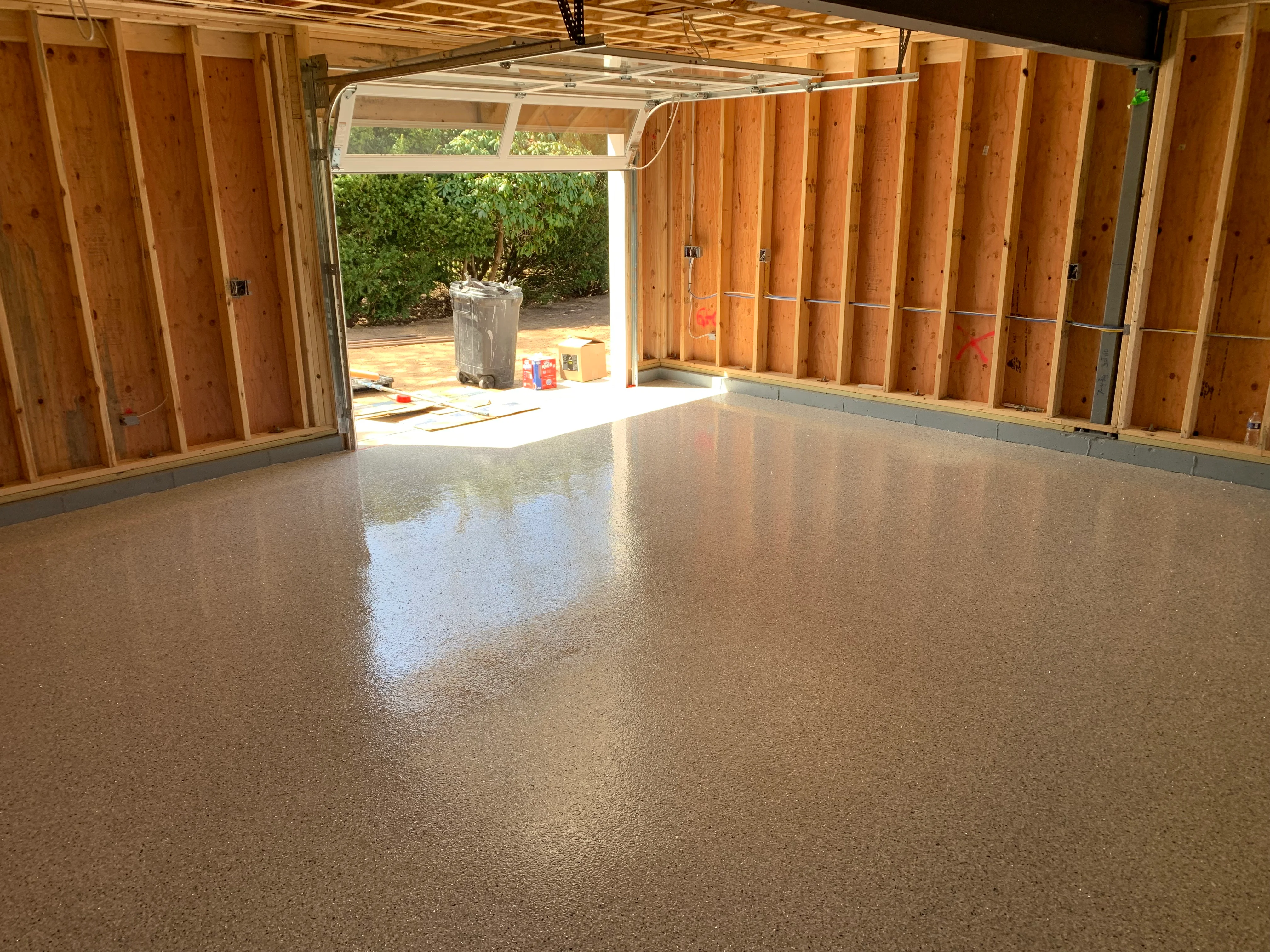 Polished epoxy garage floor with light tan aggregate finish in two-car garage space