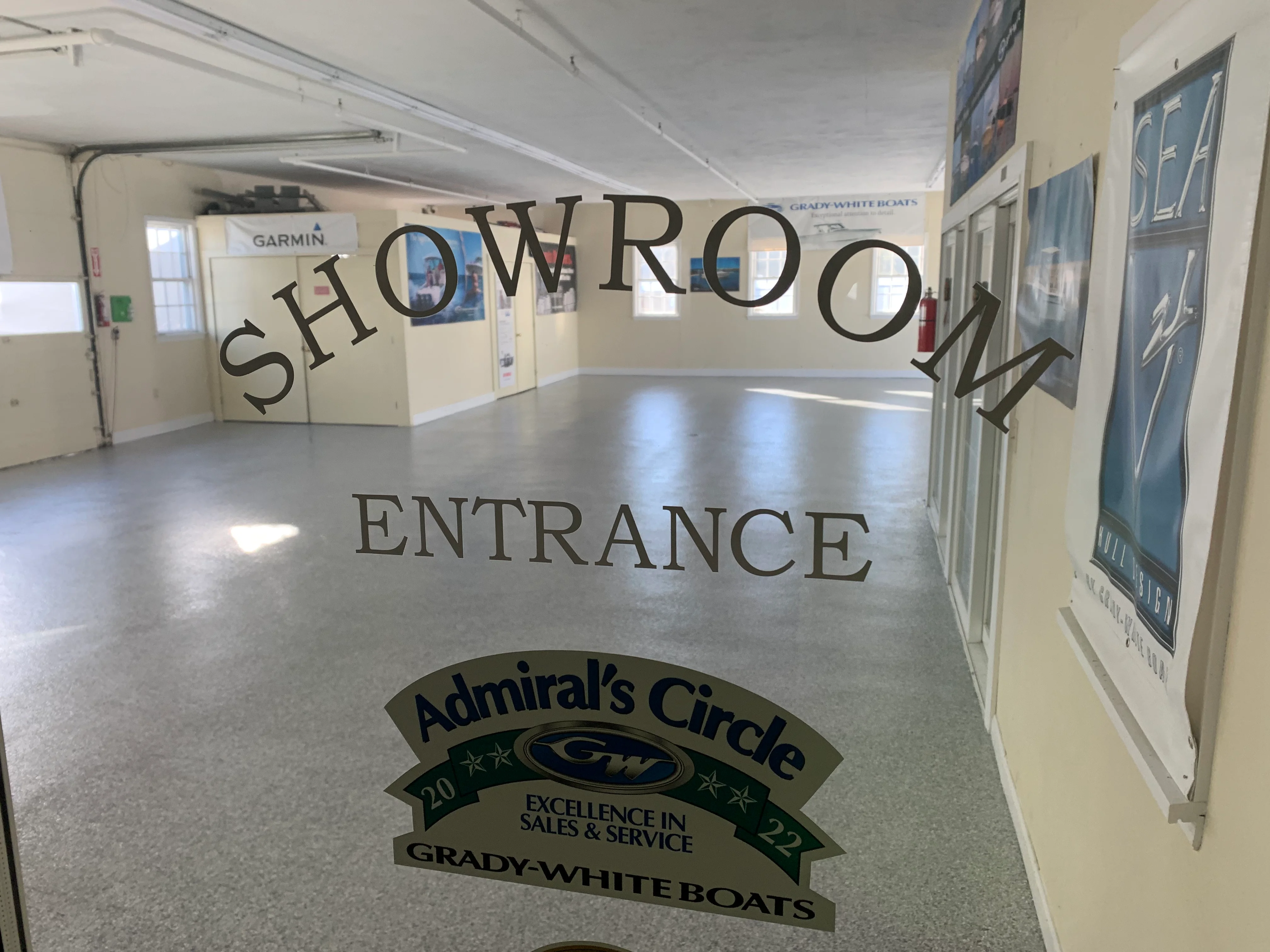 Epoxy showroom floor with custom vinyl graphics, Admiral's Circle logo, and entrance text