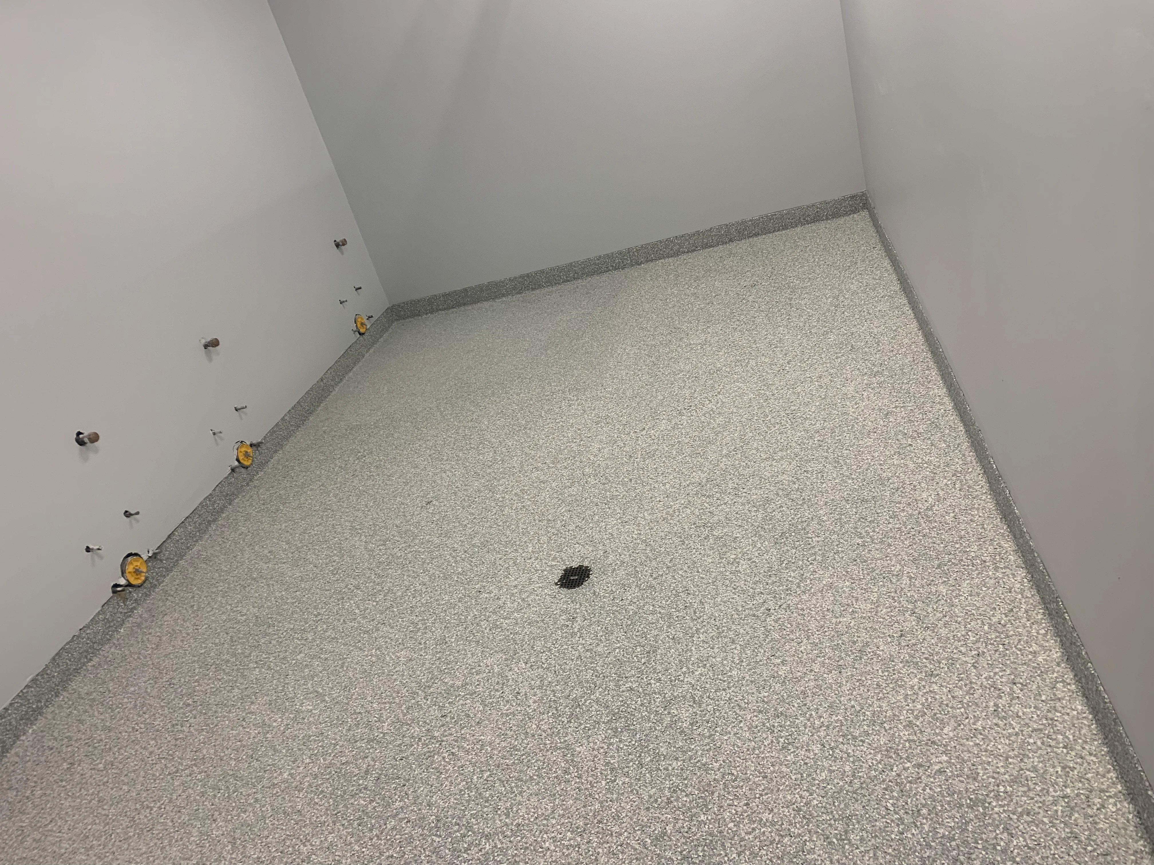 Epoxy gravel floor with gray border trim and anchor points installed in interior space