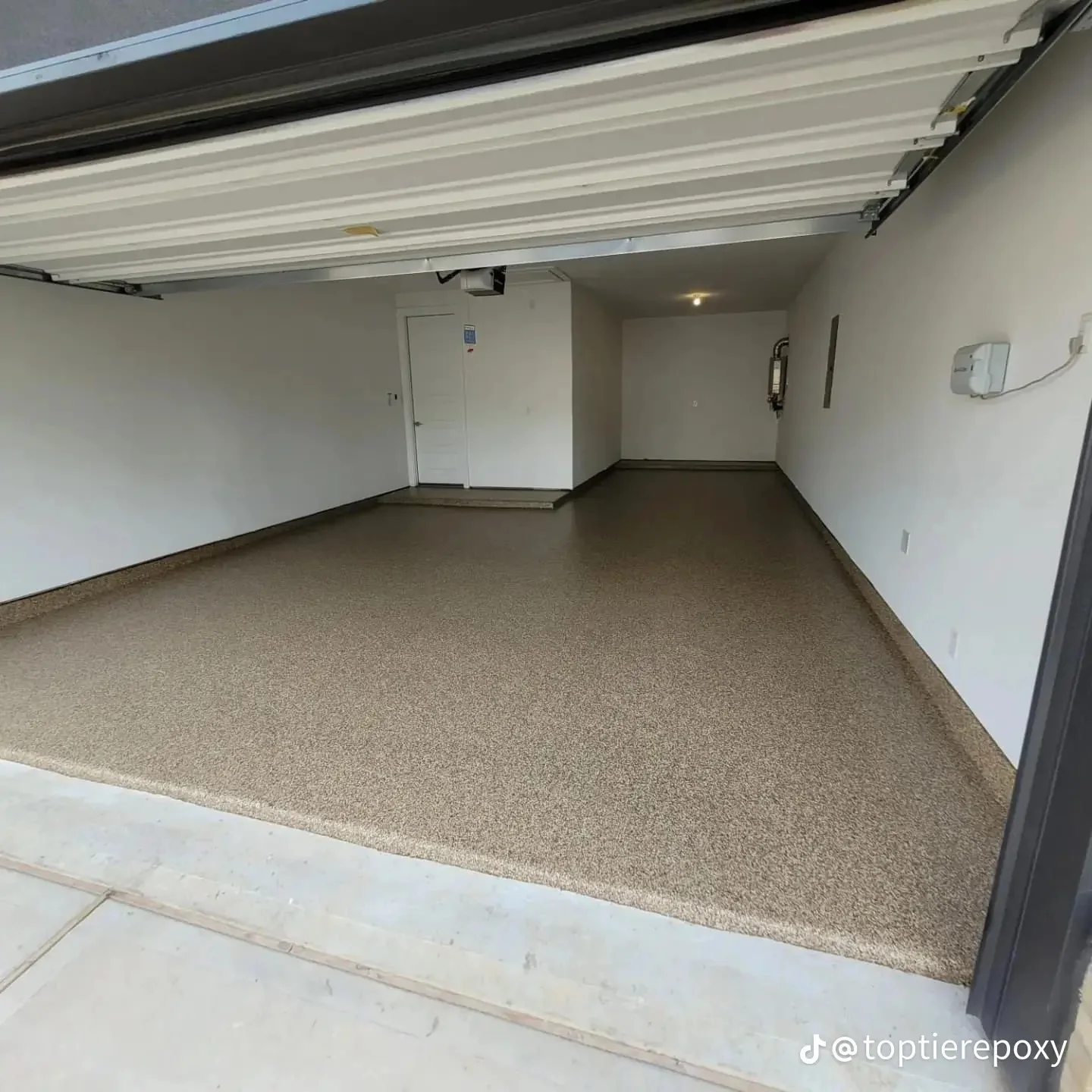 Finished epoxy garage floor with neutral beige coating and white walls